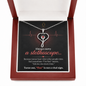 Stethoscope heart necklace with red crystal displayed in lighted wood-tone luxury gift box
