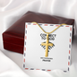 Stainless steel pendant beside open Bible and candle
