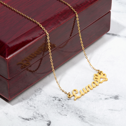 Gold necklace with 'Luna' pendant on a marble surface with a red jewelry box.