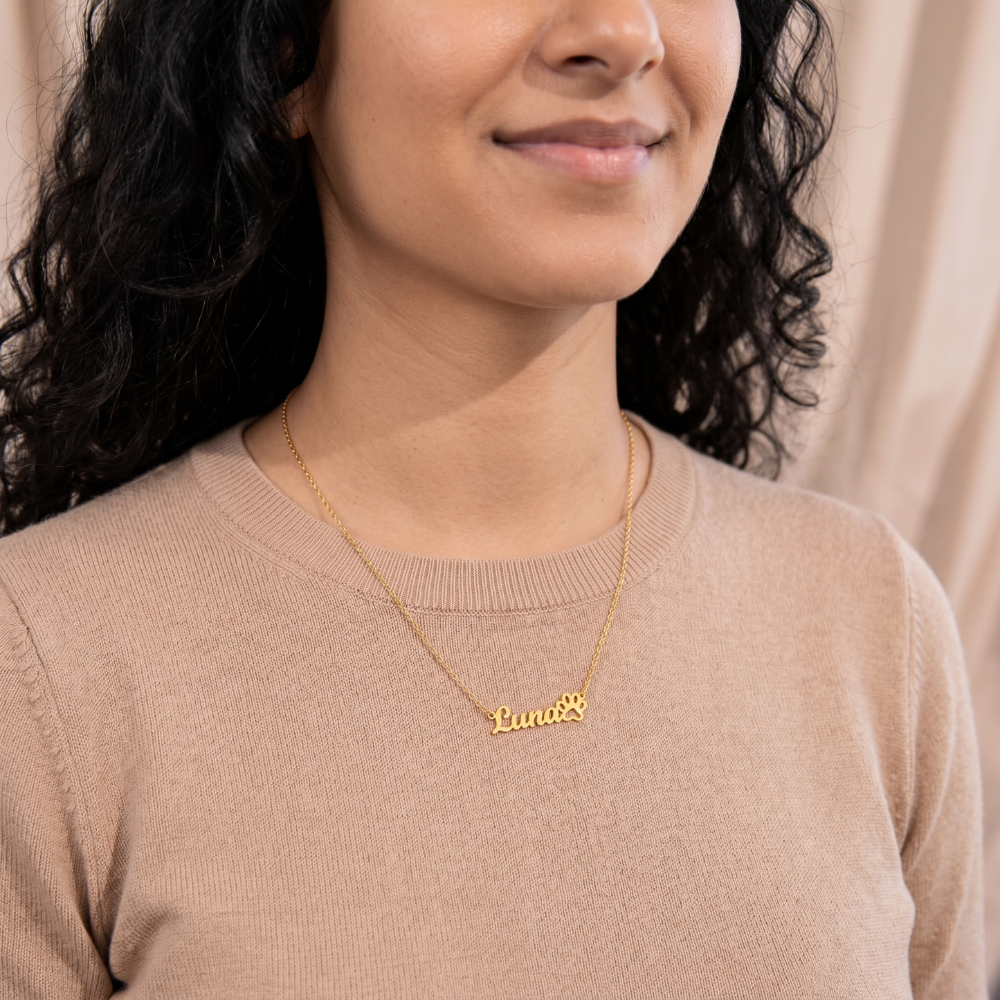 Woman wearing a gold necklace with 'Luna' engraved on it against a neutral background