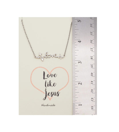 Necklace with 'love like Jesus' message on a card with a ruler for scale.