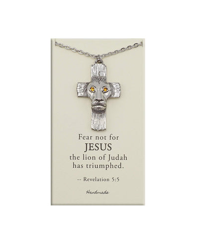 Silver cross necklace with lion head design on a beige card with text, on a white background