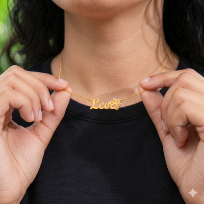 Person holding a gold necklace with 'Leo' and paw print design.