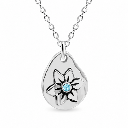 A silver teardrop pendant necklace featuring a stylized flower design with a small round light blue gemstone at the center, shown on a white background.