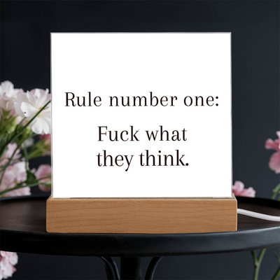 “F*ck What They Think” acrylic plaque on desk beside laptop and coffee cup for boss energy setup.