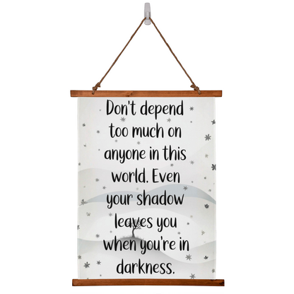 Wood framed quote tapestry reading ‘Don’t depend too much on anyone…’ hanging on wall
