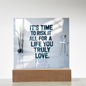 Motivational plaque placed beside framed photos and plants for cozy home inspiration.
