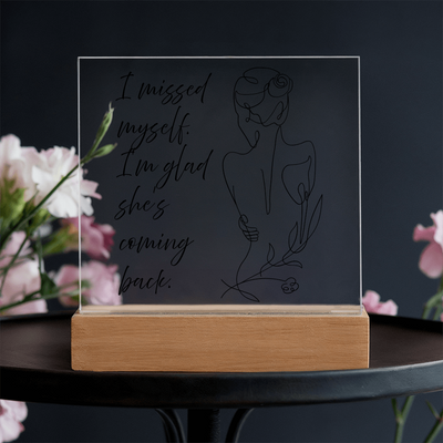Woman holding LED frame with empowering quote about self return