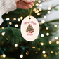 Hand hanging the Merry & Bright 2026 pink Christmas tree ornament on a lit tree