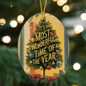 Flat lay of “It’s the Most Wonderful Time of the Year” ornament beside pine and lights