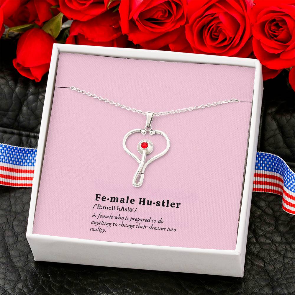 Close-up of polished stainless steel stethoscope pendant featuring red Swarovski crystal detail.