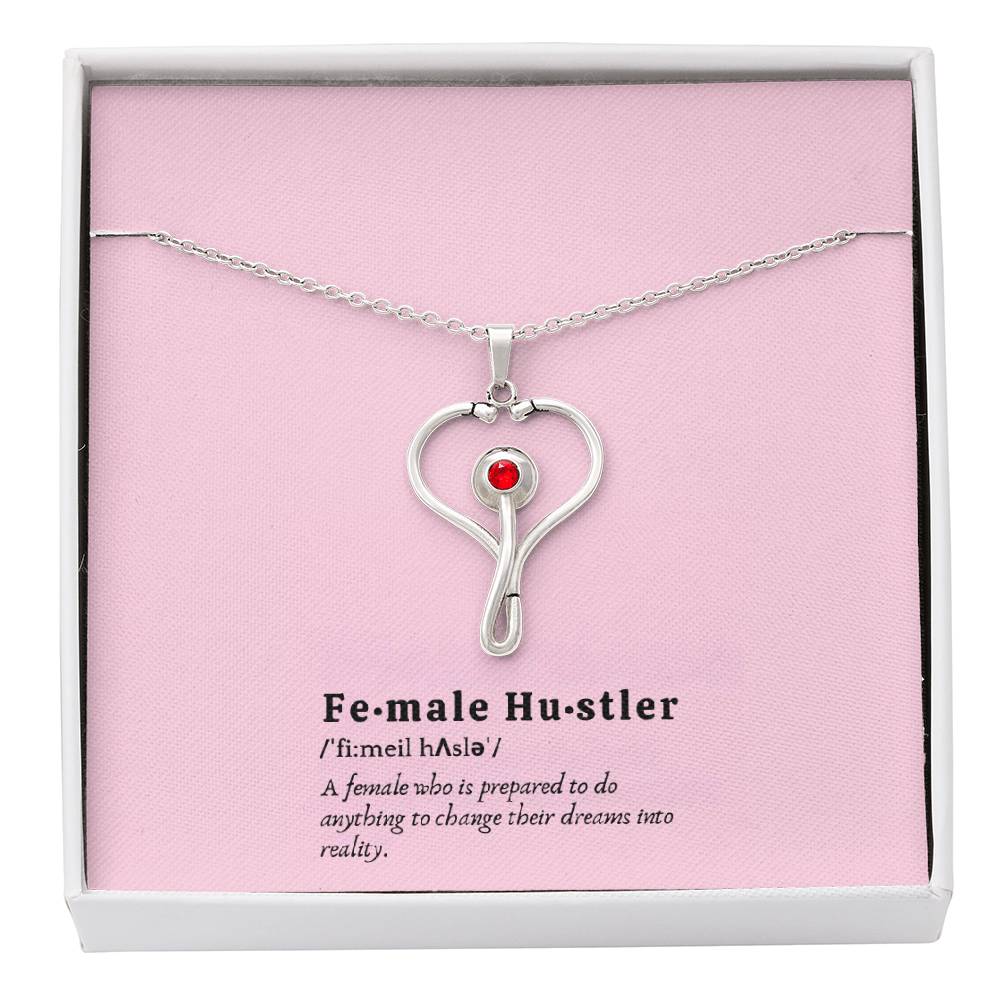 Female Hustler stethoscope necklace with heart-shaped pendant and red Swarovski crystal.